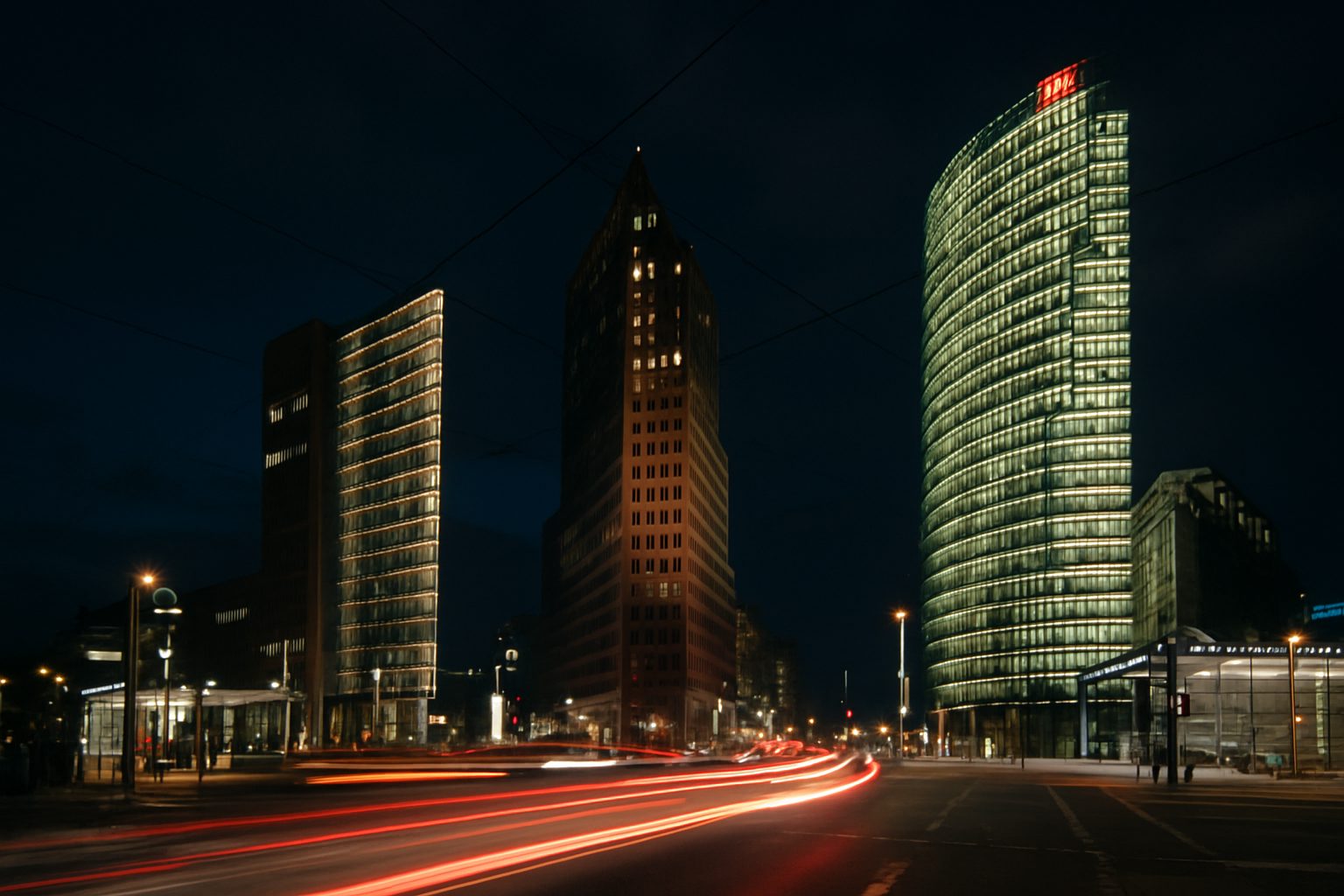 Potsdamer Platz in Berlin at night from street level, towers above and light trails across the junction