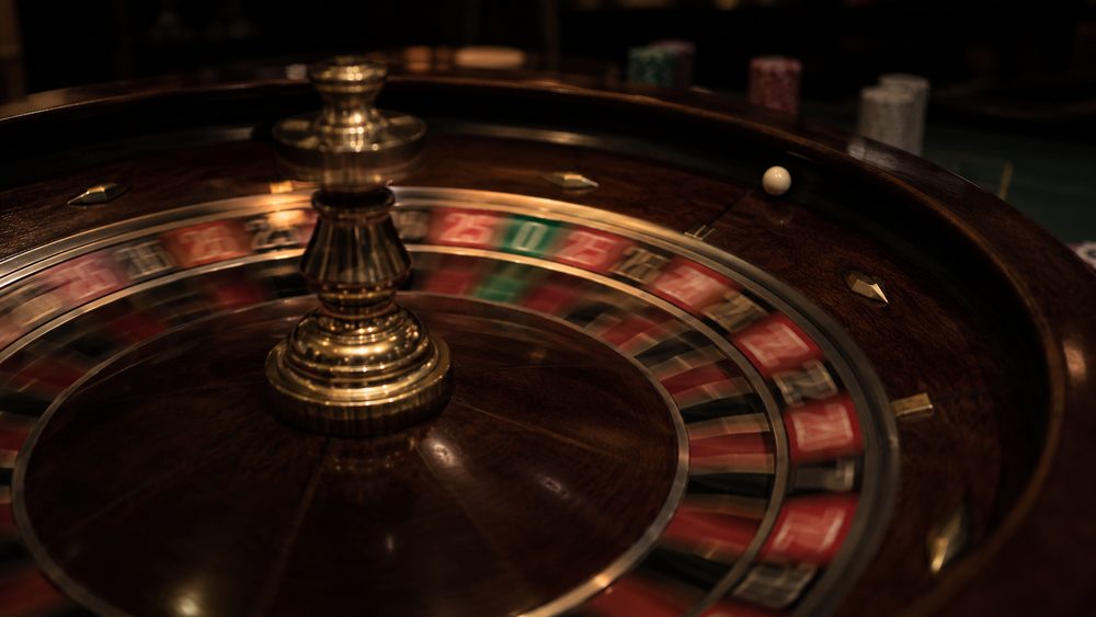 A close view of a European single-zero roulette wheel with the ball still spinning in the track, the green zero pocket in focus